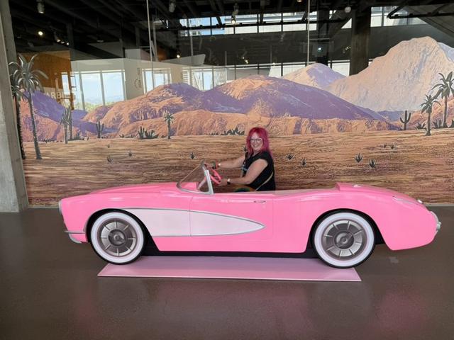 Kristin behind the wheel of a life-size pink convertible