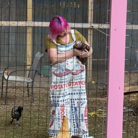Kristin in the backyard chicken run, holding one of her hens
